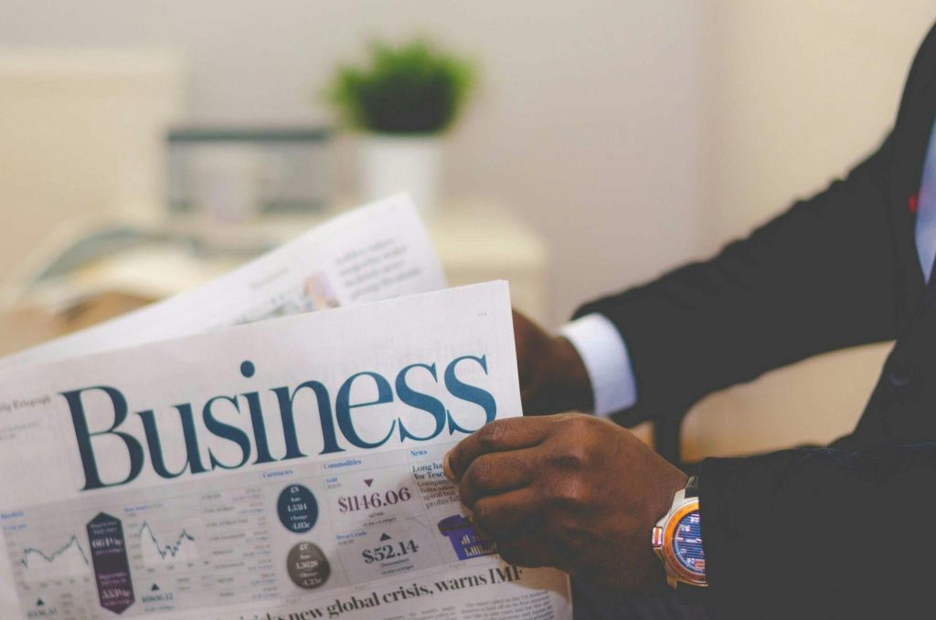 A man wearing a suit is holding a newspaper. 